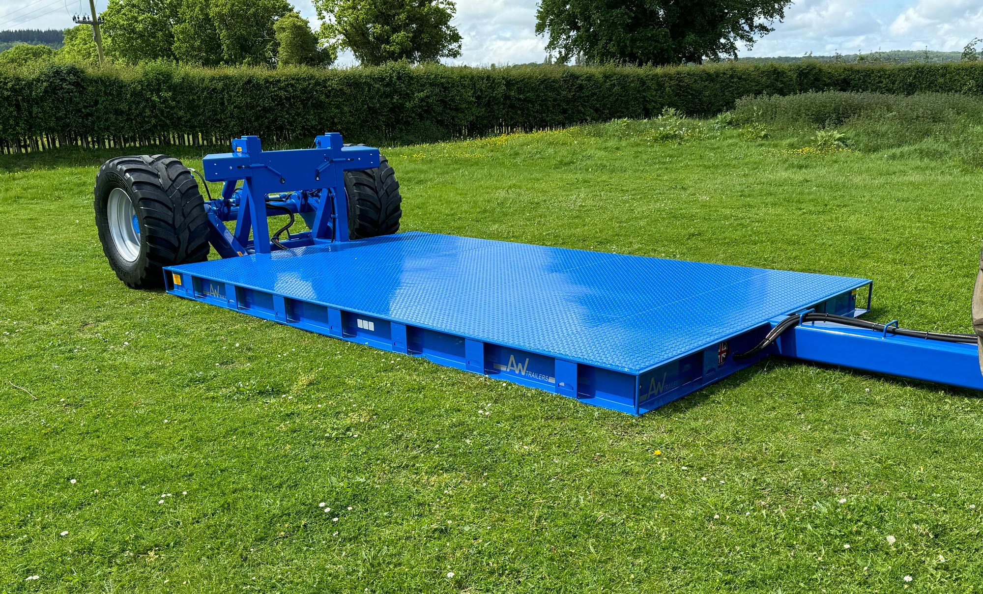 Blue trailer low on the ground in a grass field