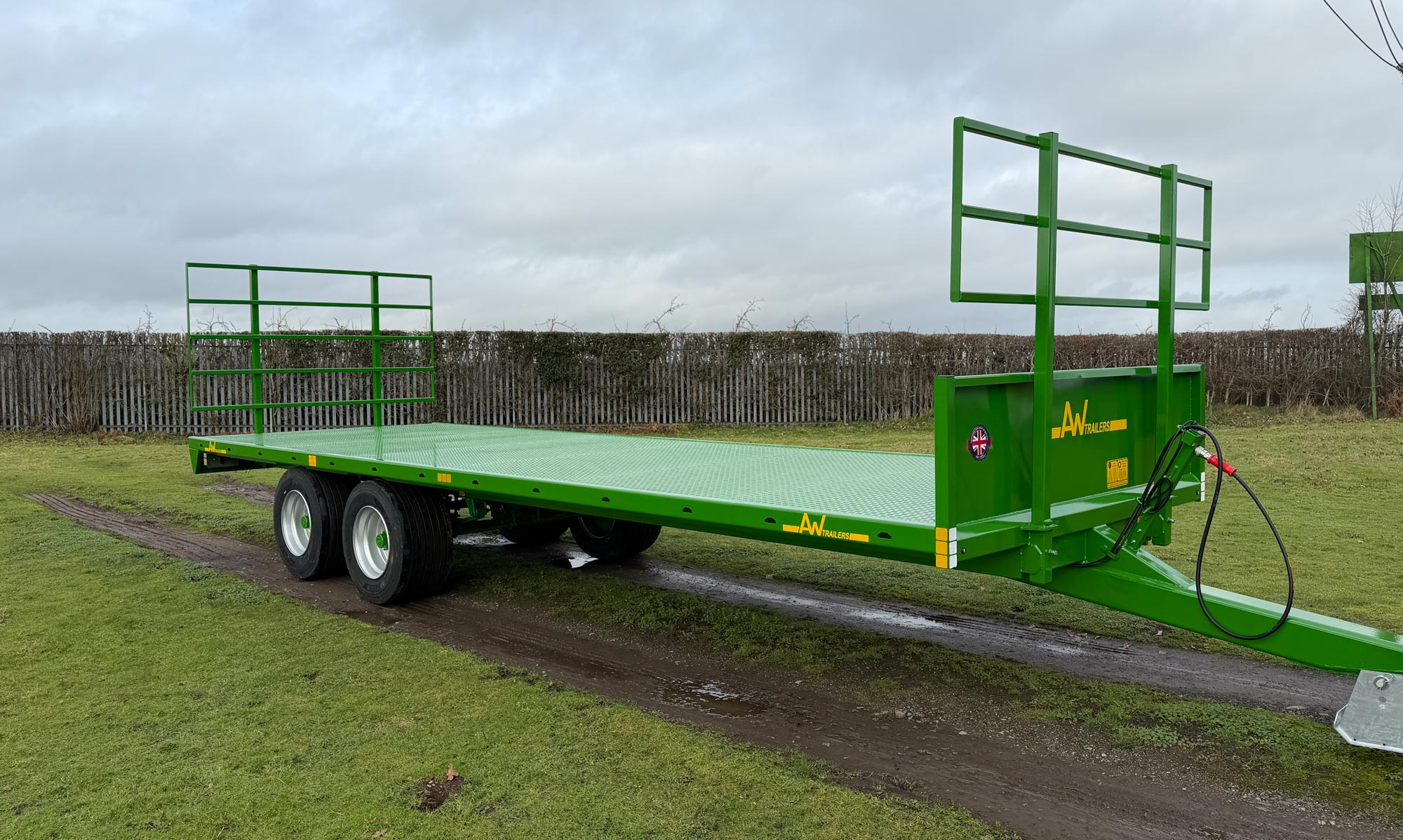 Long flat green trailer on a muddy track