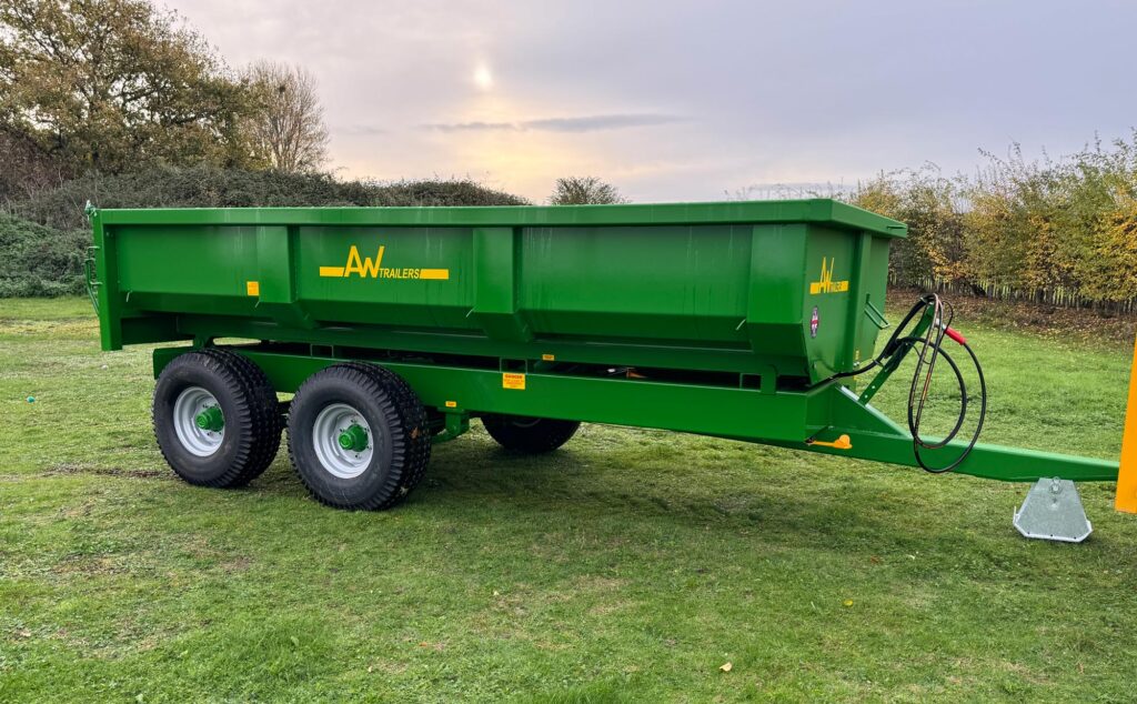 Large green trailer in a green grass field with a sunset