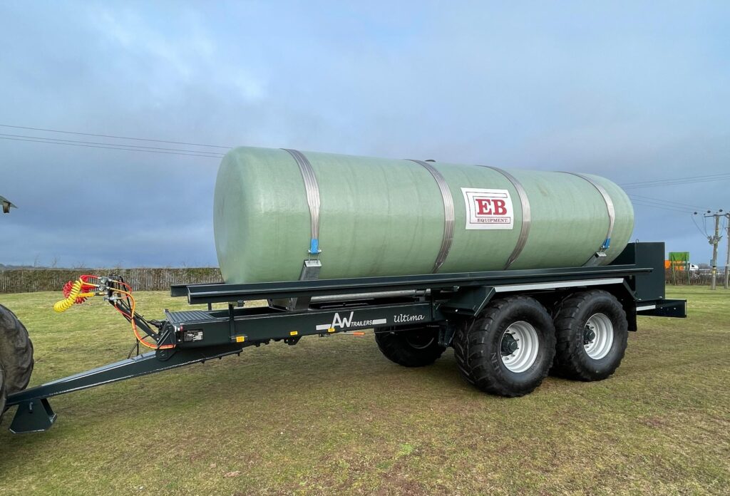 A large green tank in a field being carried on a trailer