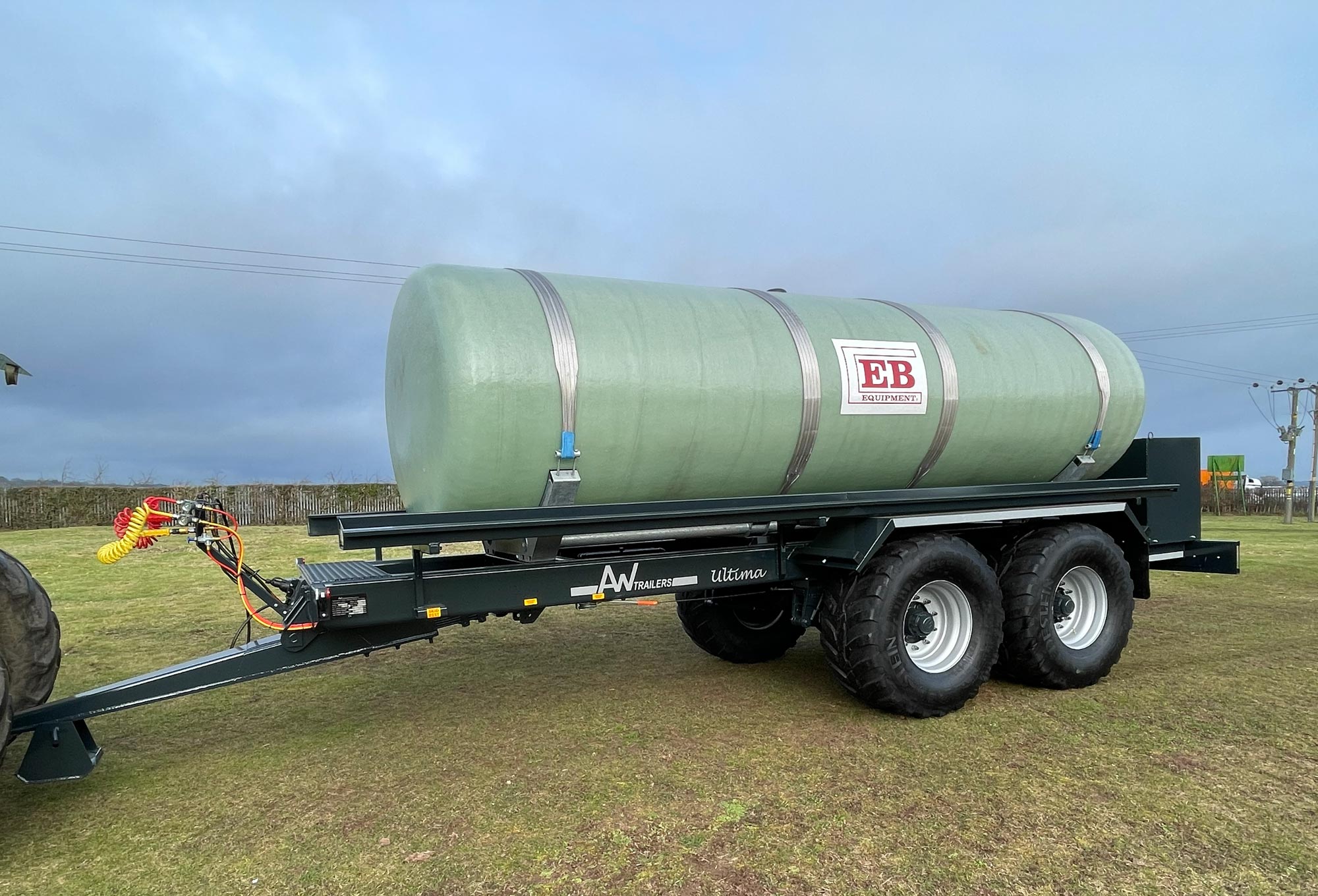 A large green tank in a field being carried on a trailer
