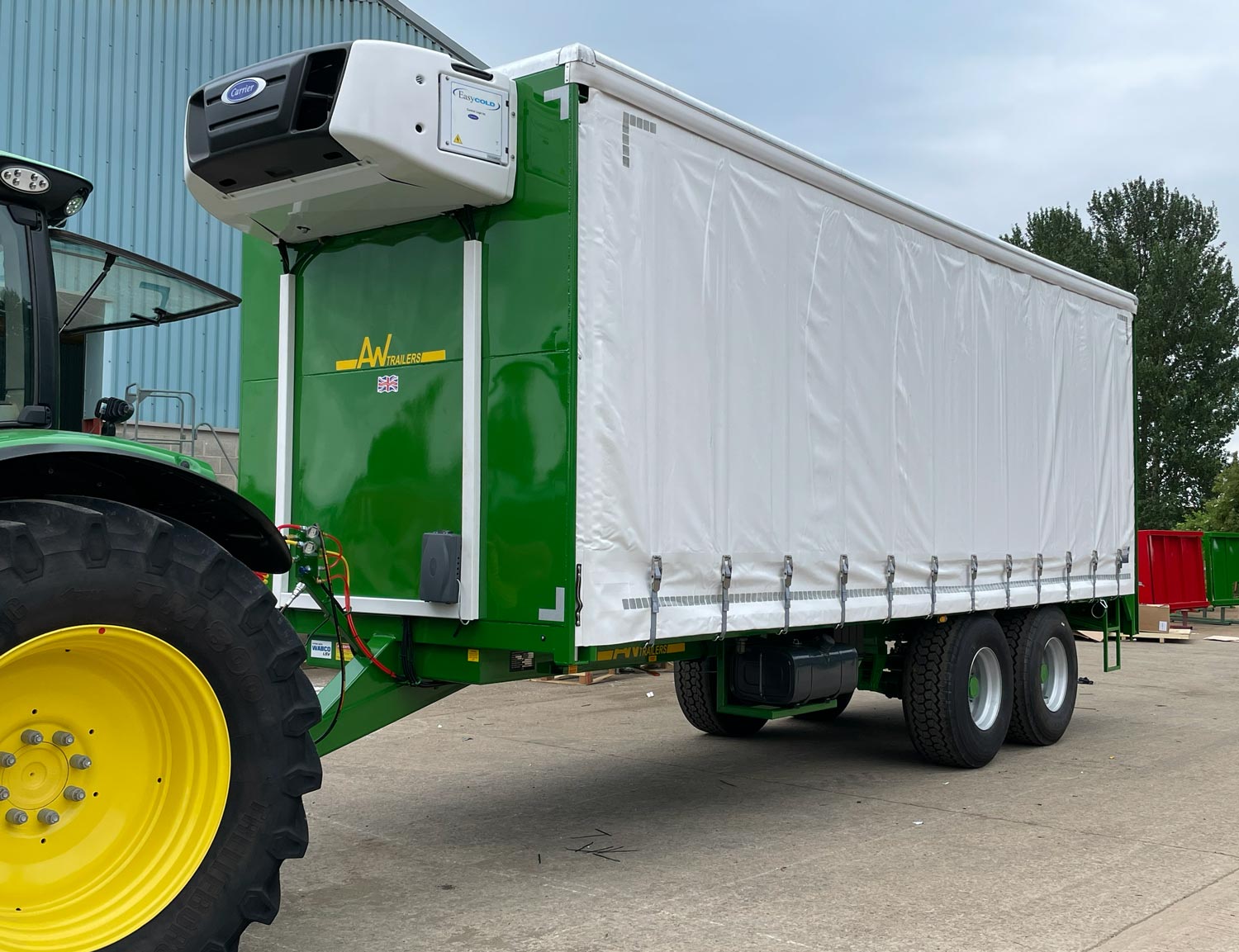 A large green trailer is being pulled by a tractor