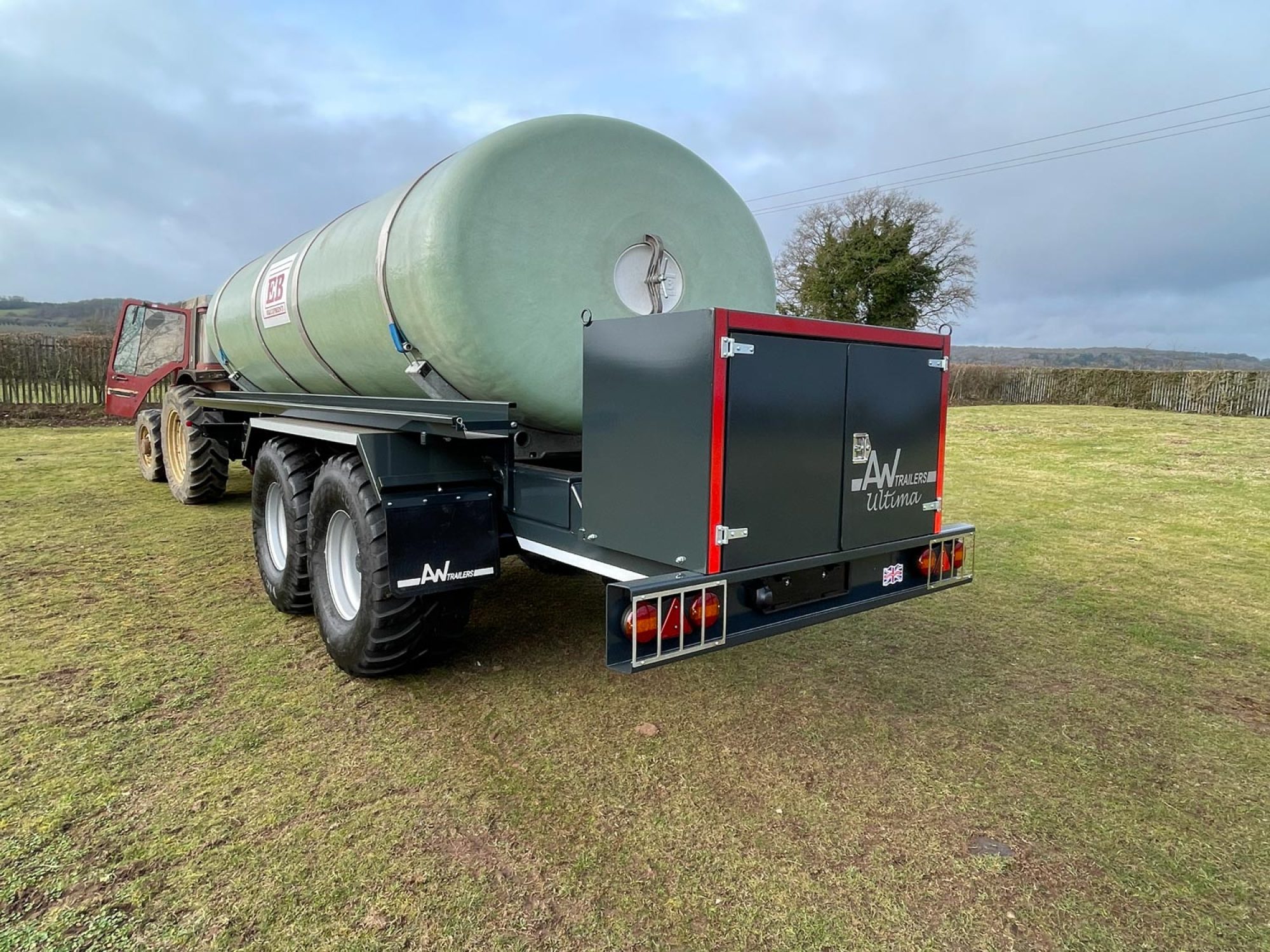 A large green tank in a field being carried on a trailer