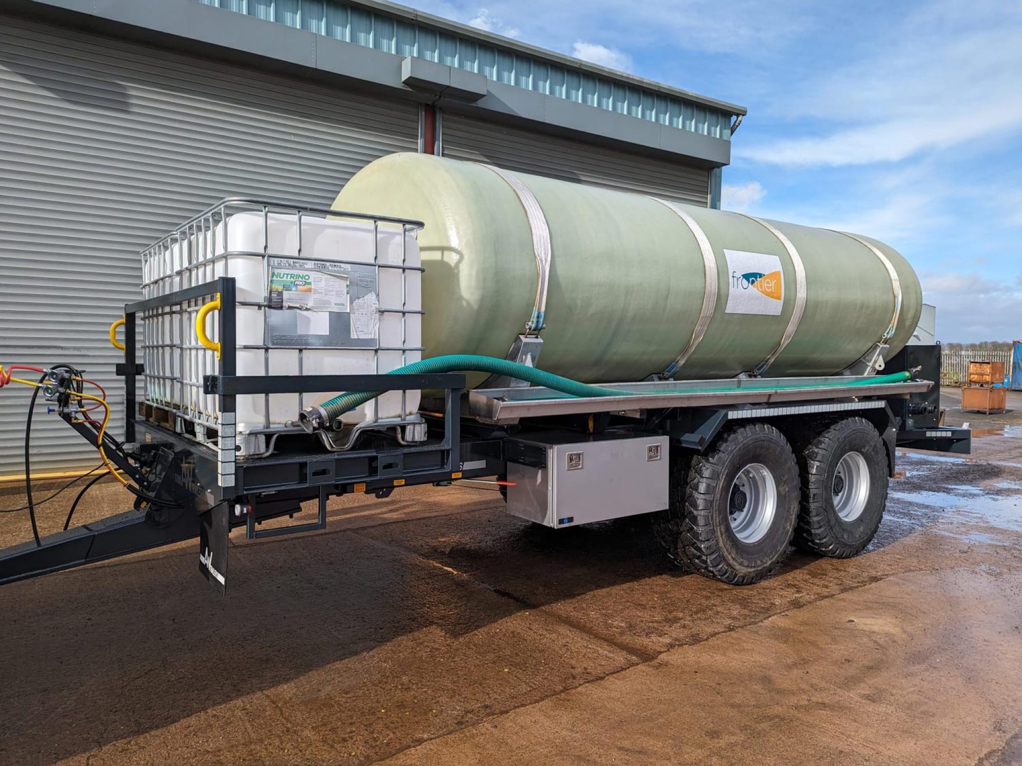 A large green tank in a field being carried on a trailer