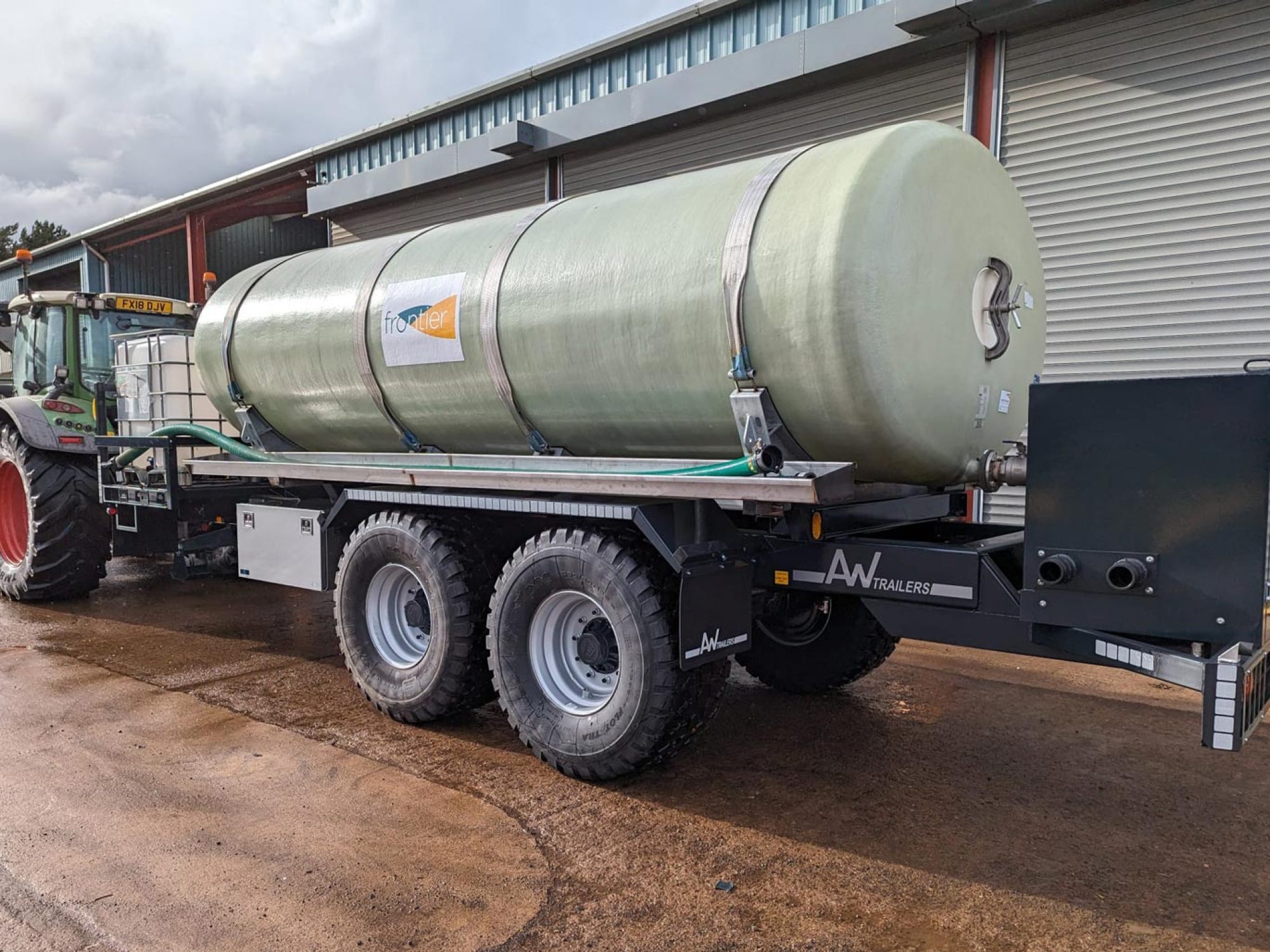 A large green tank in a field being carried on a trailer