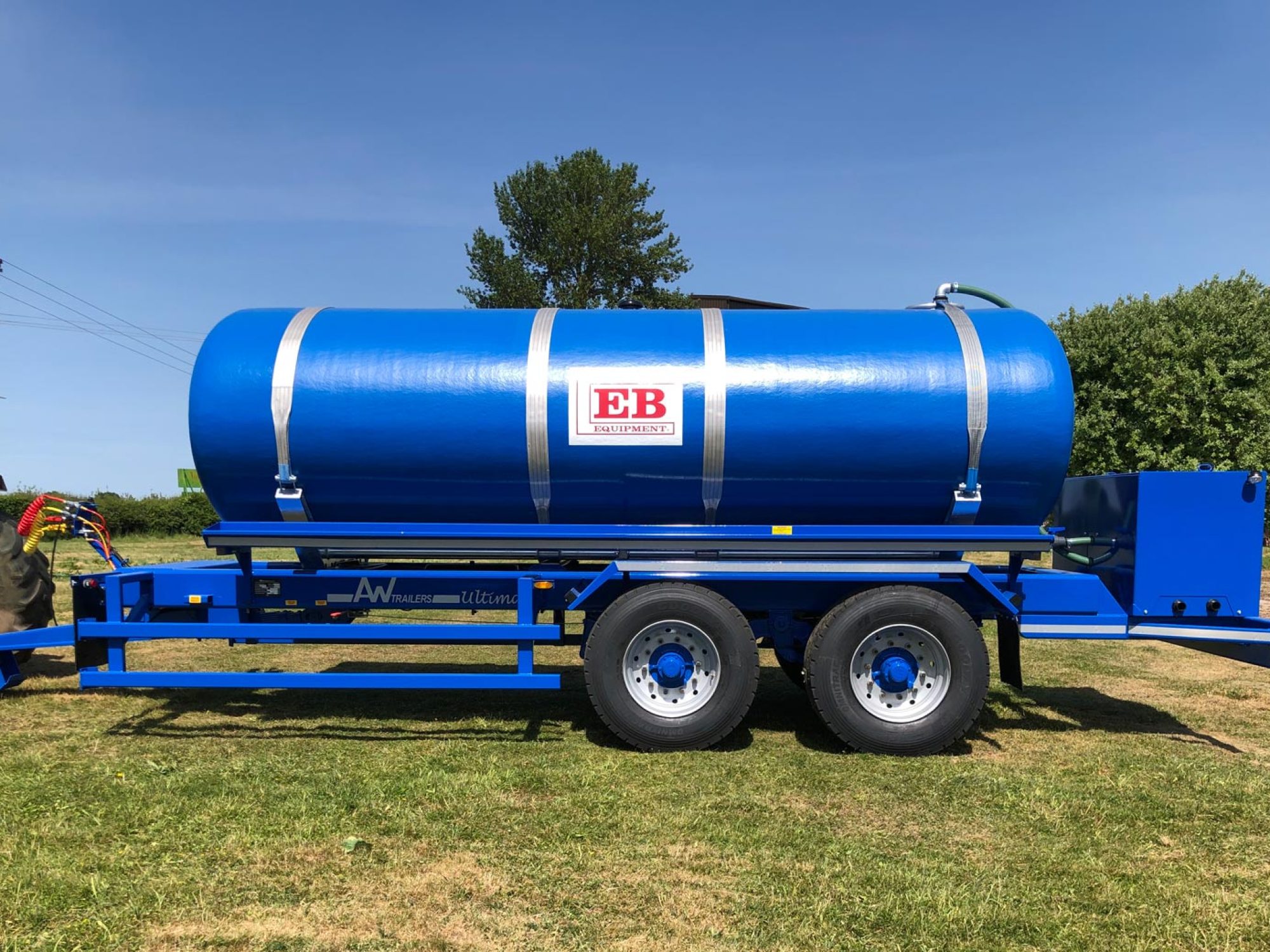 A large blue tank in a field being carried on a trailer