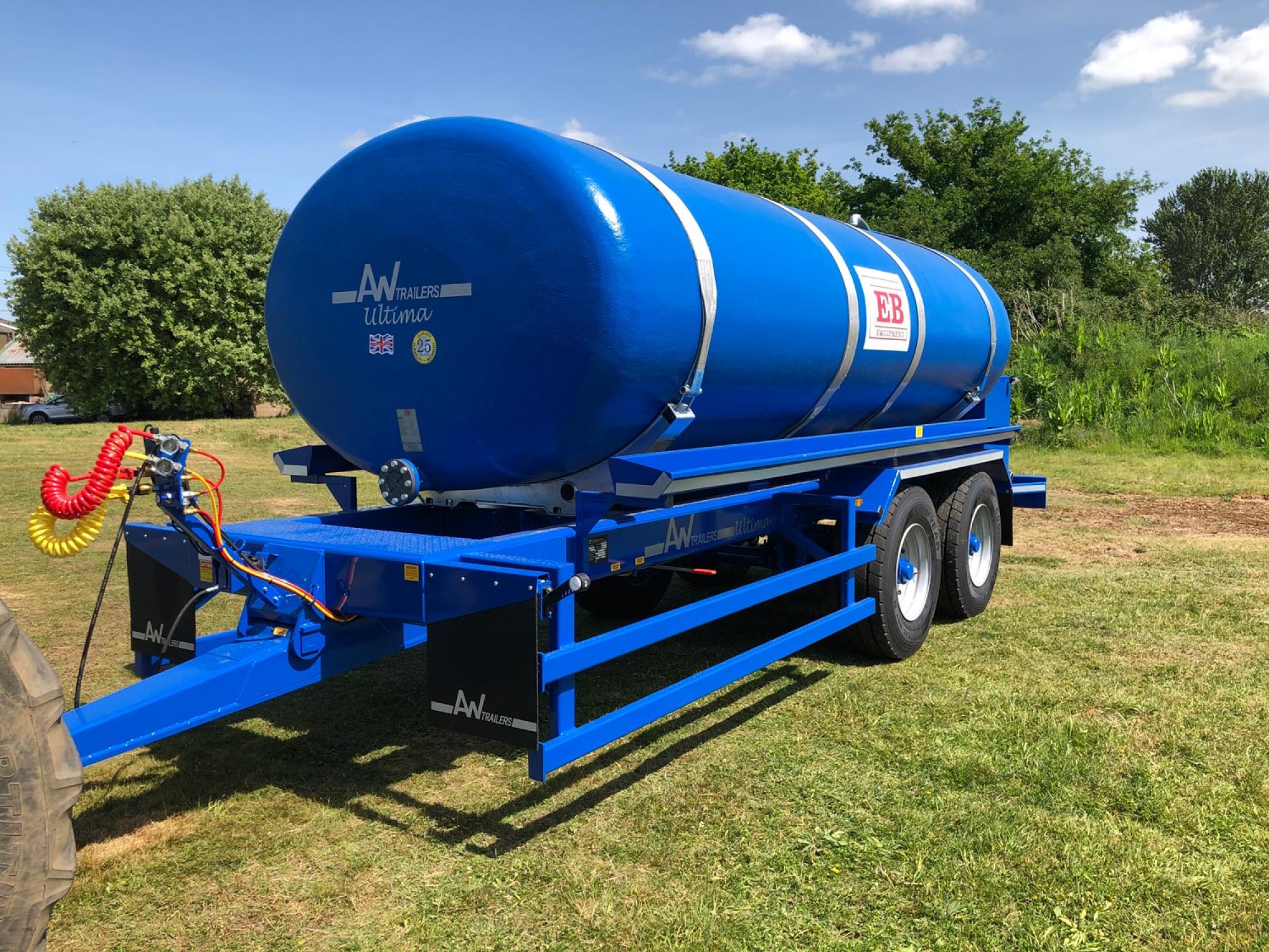 A large blue tank in a field being carried on a trailer