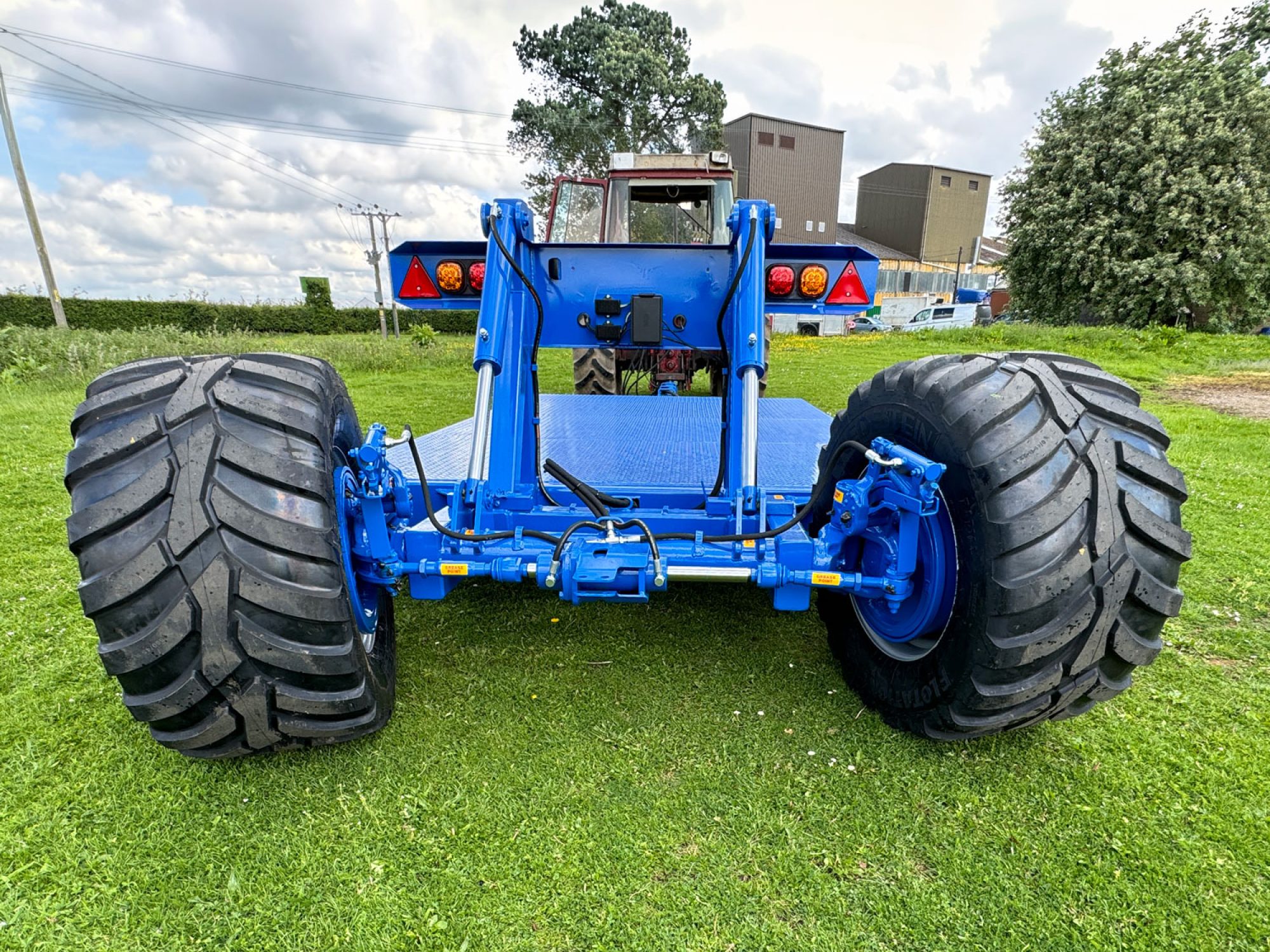 Blue flatbed trailer in a field with big tractor wheels