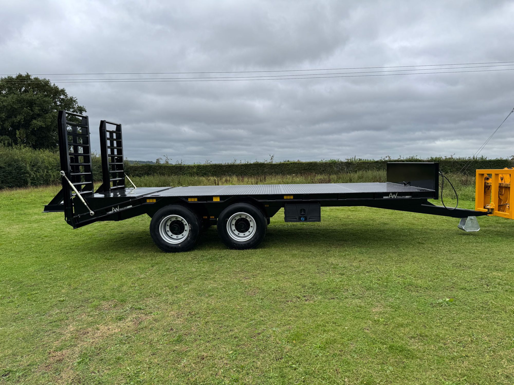 Black plant low loader trailer in a field