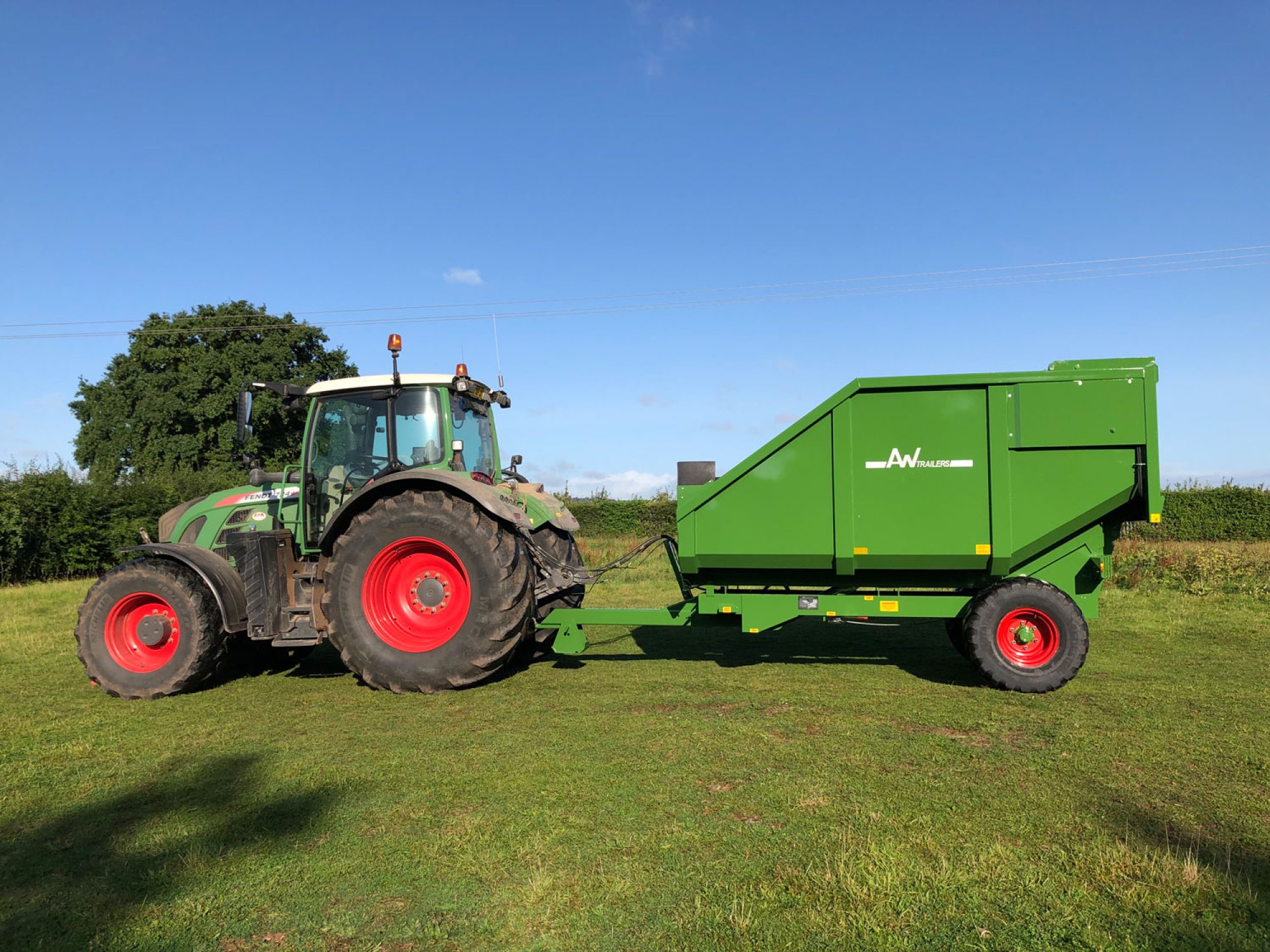 Large green trailer in a field on the back of a tractor