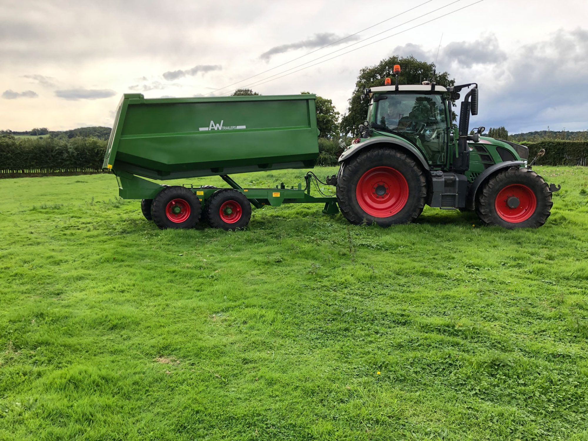 Large green trailer in a field on the back of a tractor