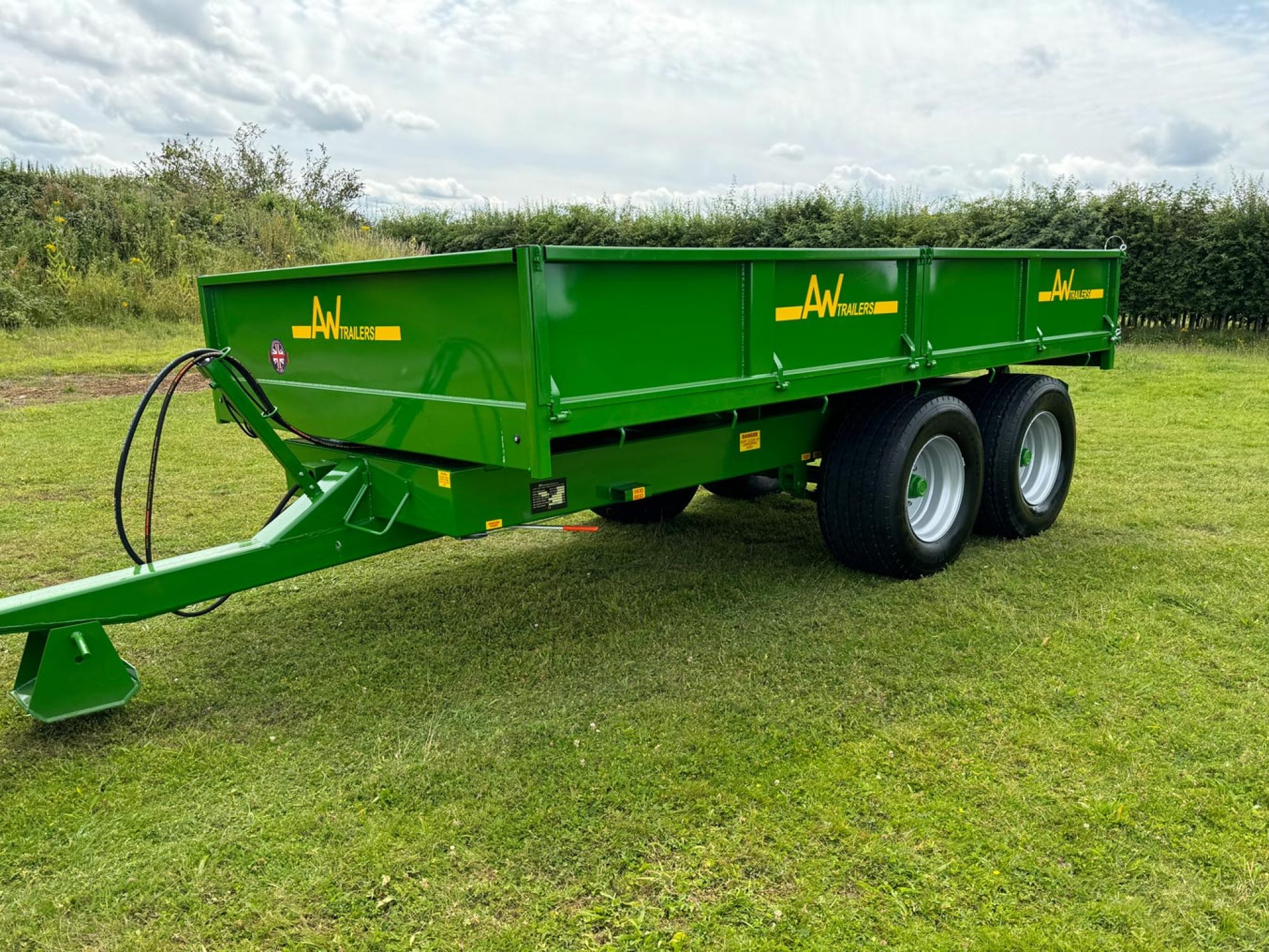Green trailer in a field with 2 big black wheels