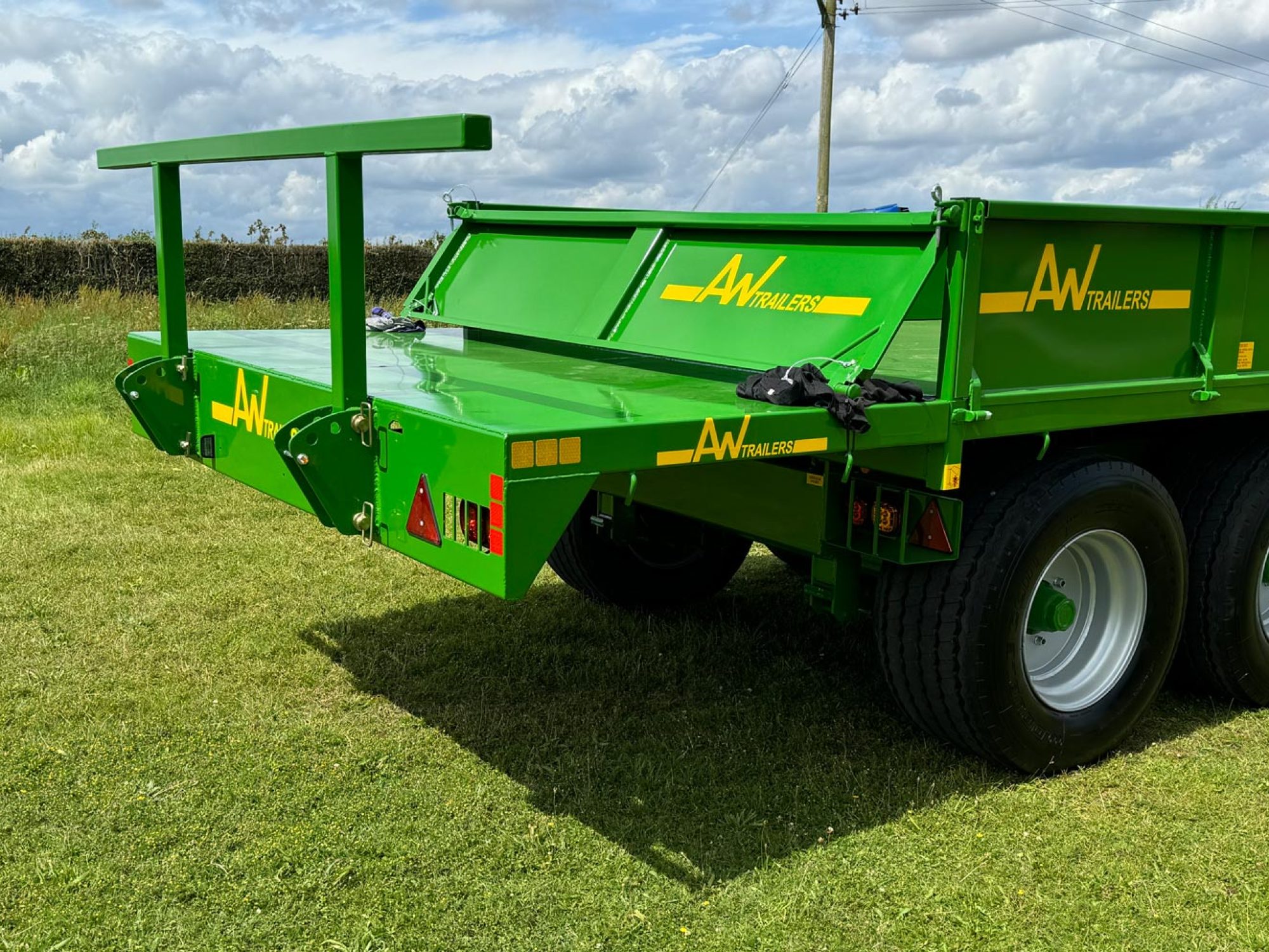 Green trailer in a field with 2 big black wheels