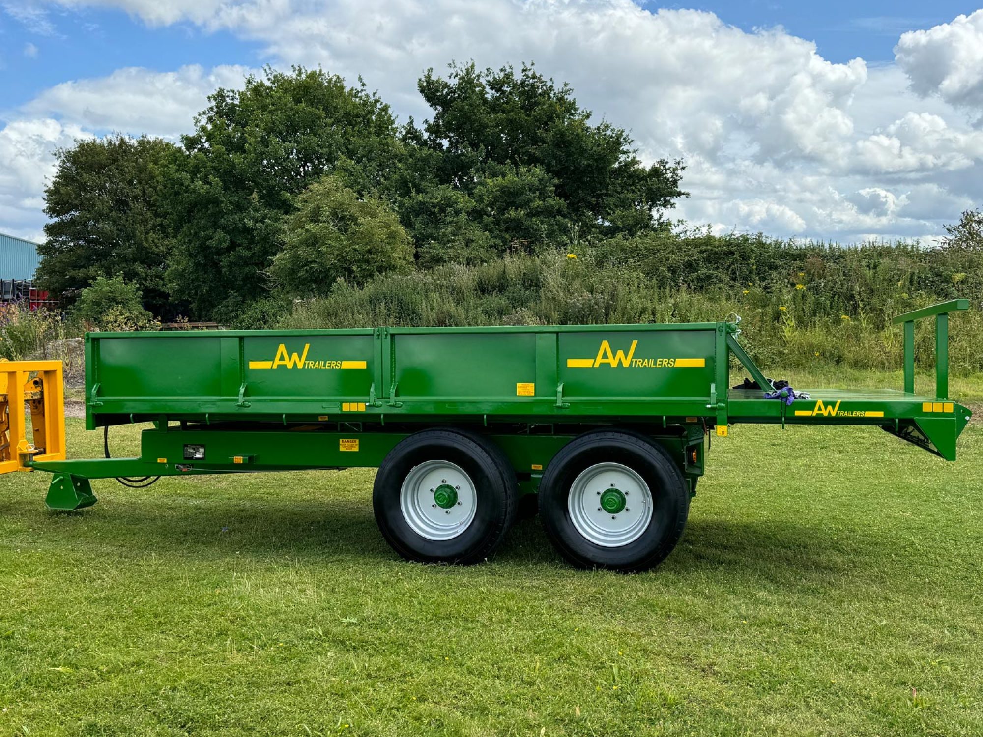 Green trailer in a field with 2 big black wheels