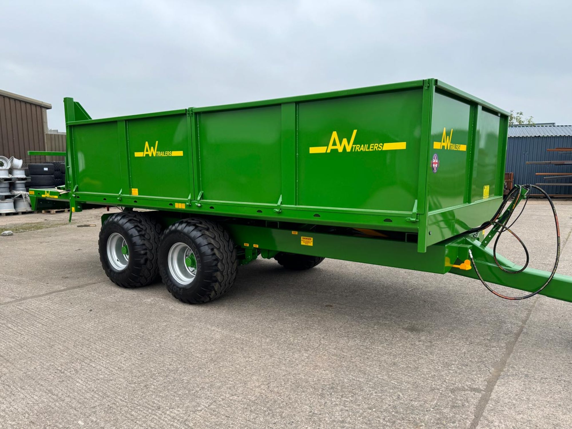 Green trailer in a field with 2 big black wheels