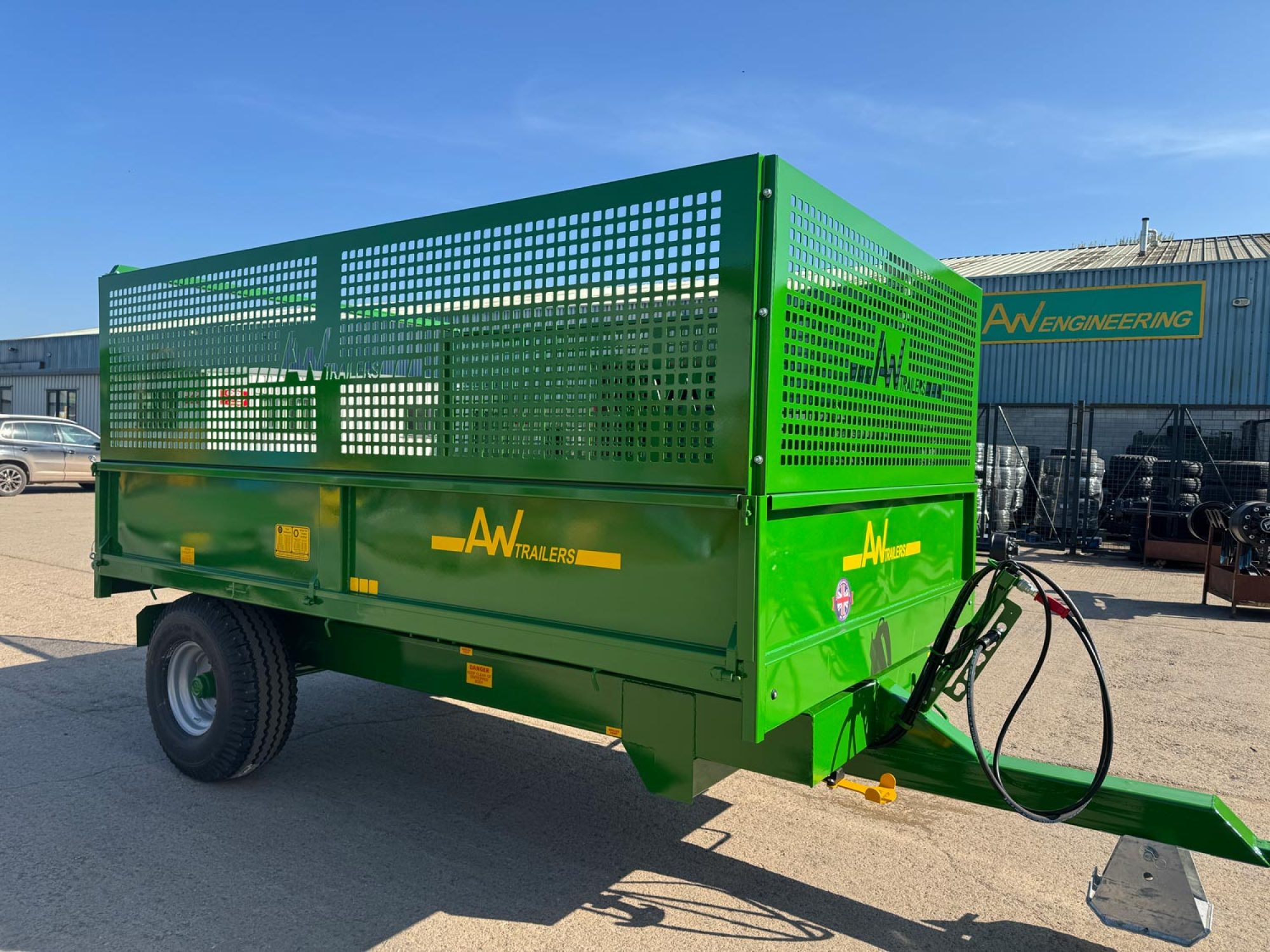 Green trailer in a field with 2 big black wheels