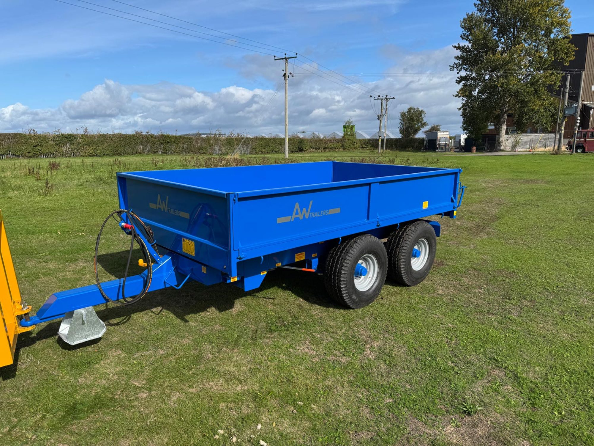 Blue trailer in a field with 2 big black wheels