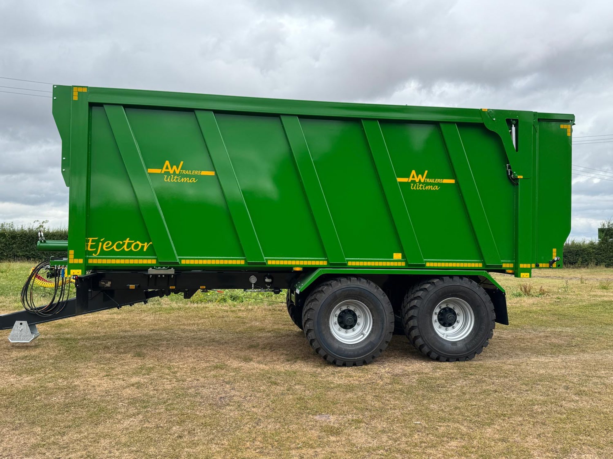 A large green trailer with large black tyres in a field