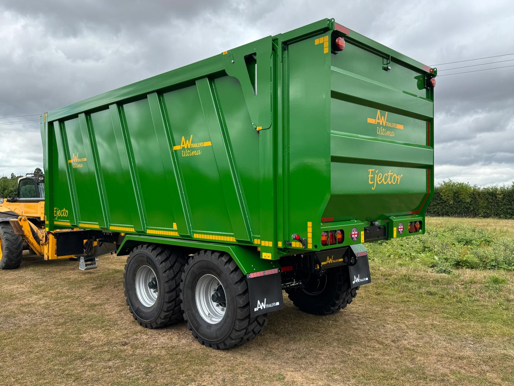 A large green trailer with large black tyres in a field