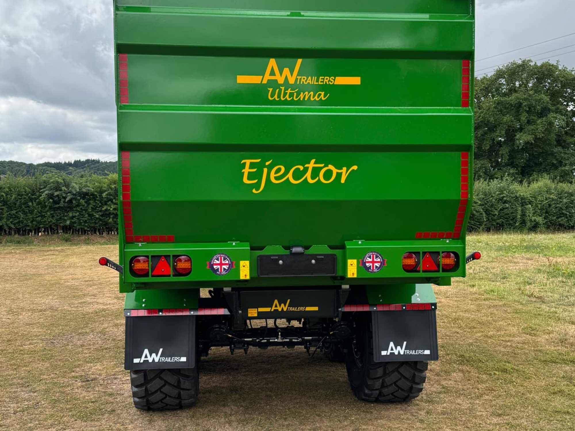 A large green trailer with large black tyres in a field