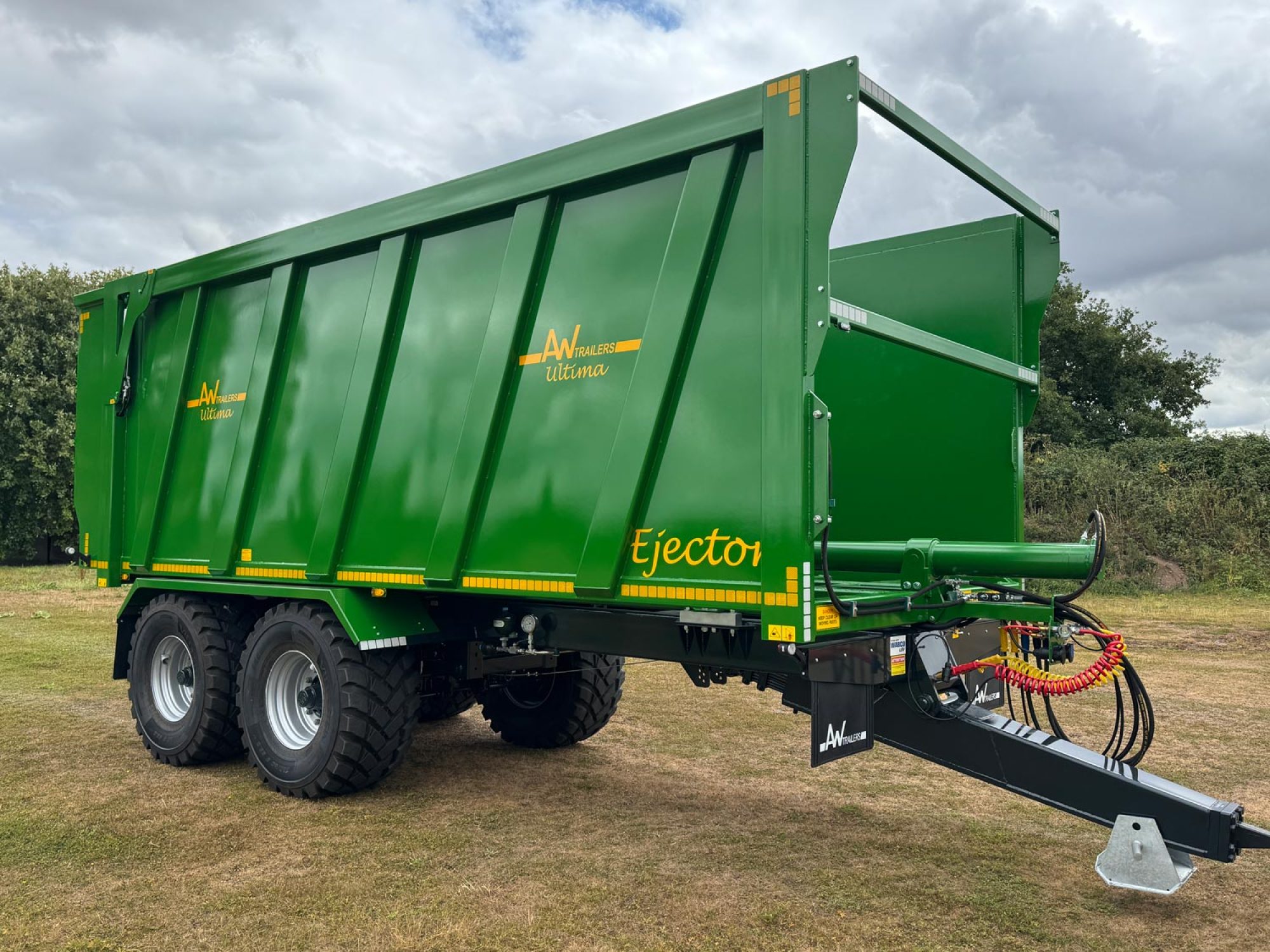 A large green trailer with large black tyres in a field