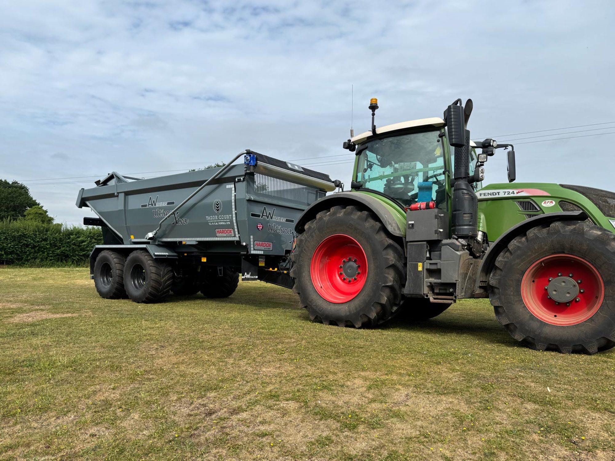 A large grey trailer connected to a green tractor in a field