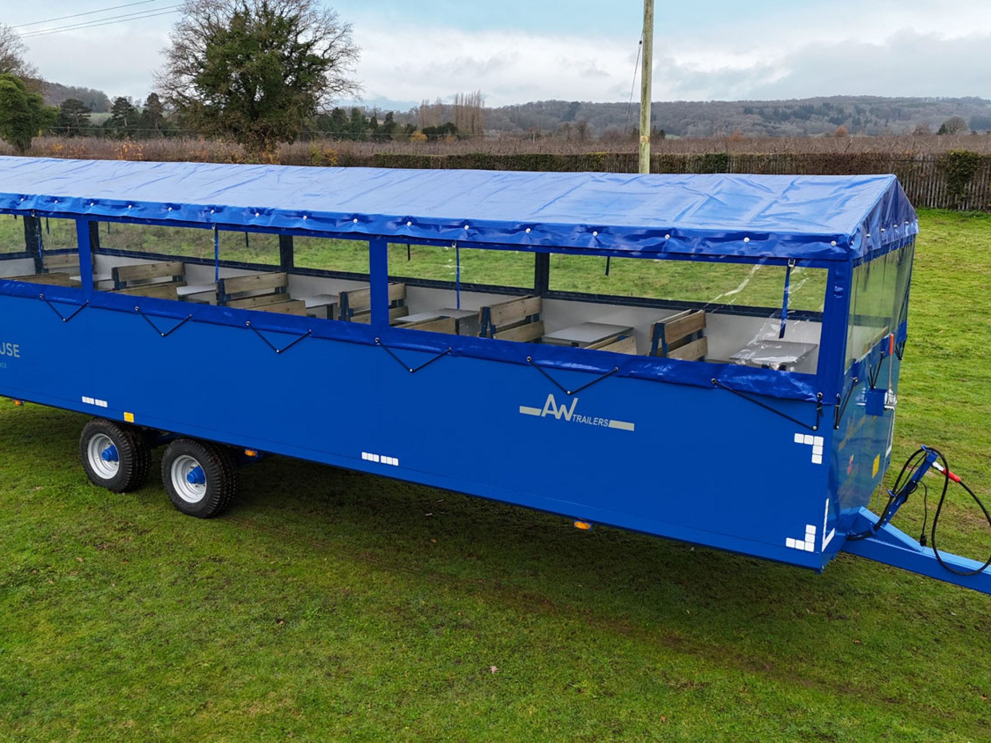 A Large blue people carrier trailer with cover on top in a field