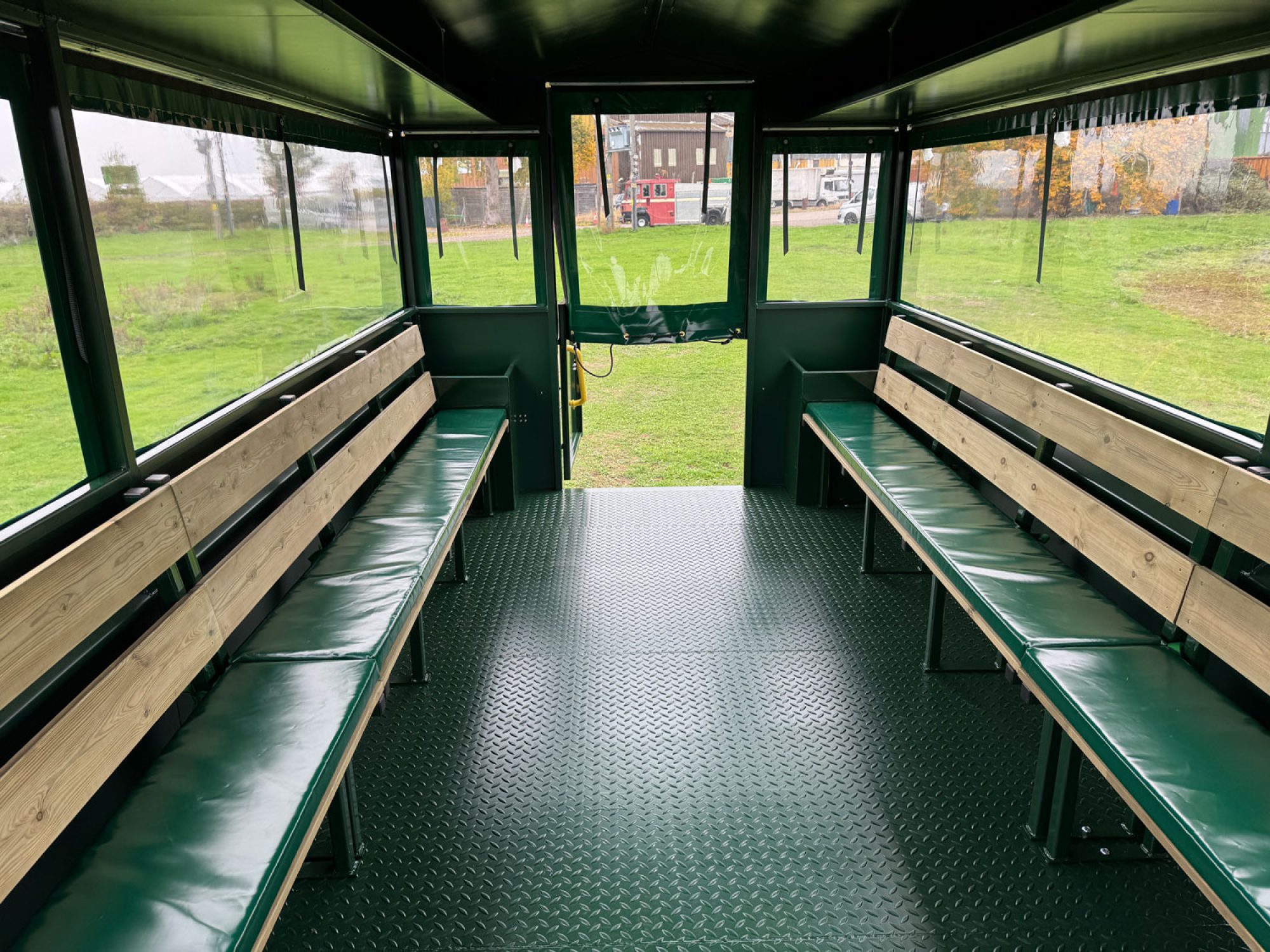 inside of a green people carrier trailer with wooden seating