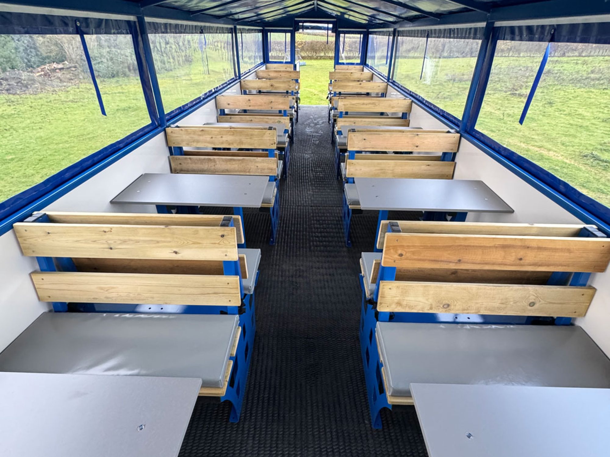 inside of a blue people carrier trailer with wooden seating