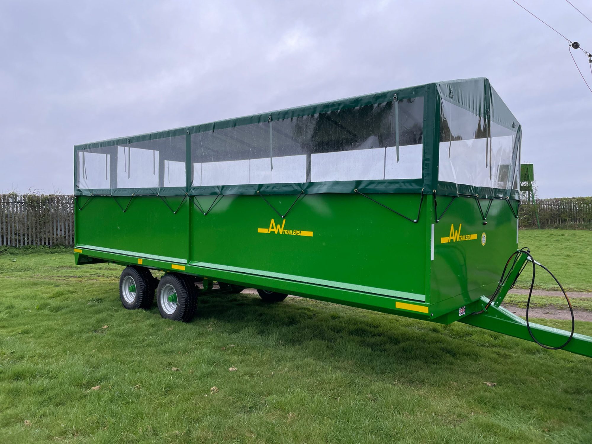A Large green people carrier trailer with cover on top in a field