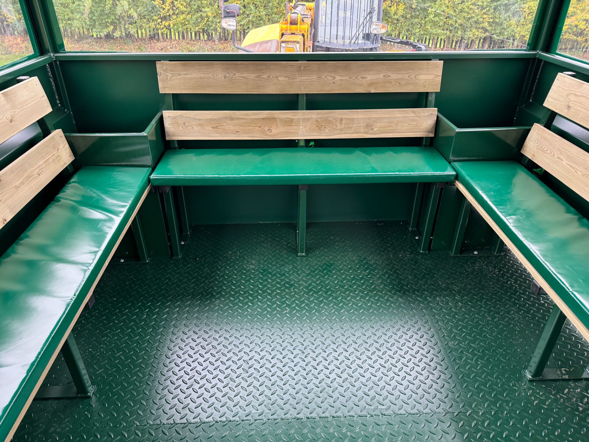 inside of a green people carrier trailer with wooden seating