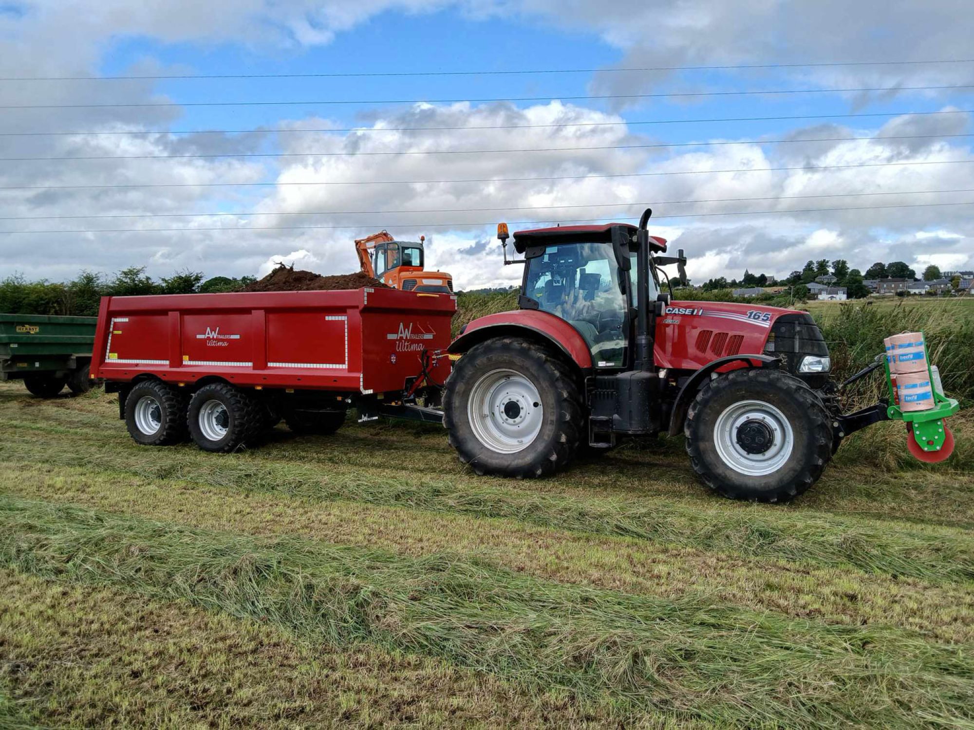 Green Stone & Rubble Trailer in a field being towed by a tractor