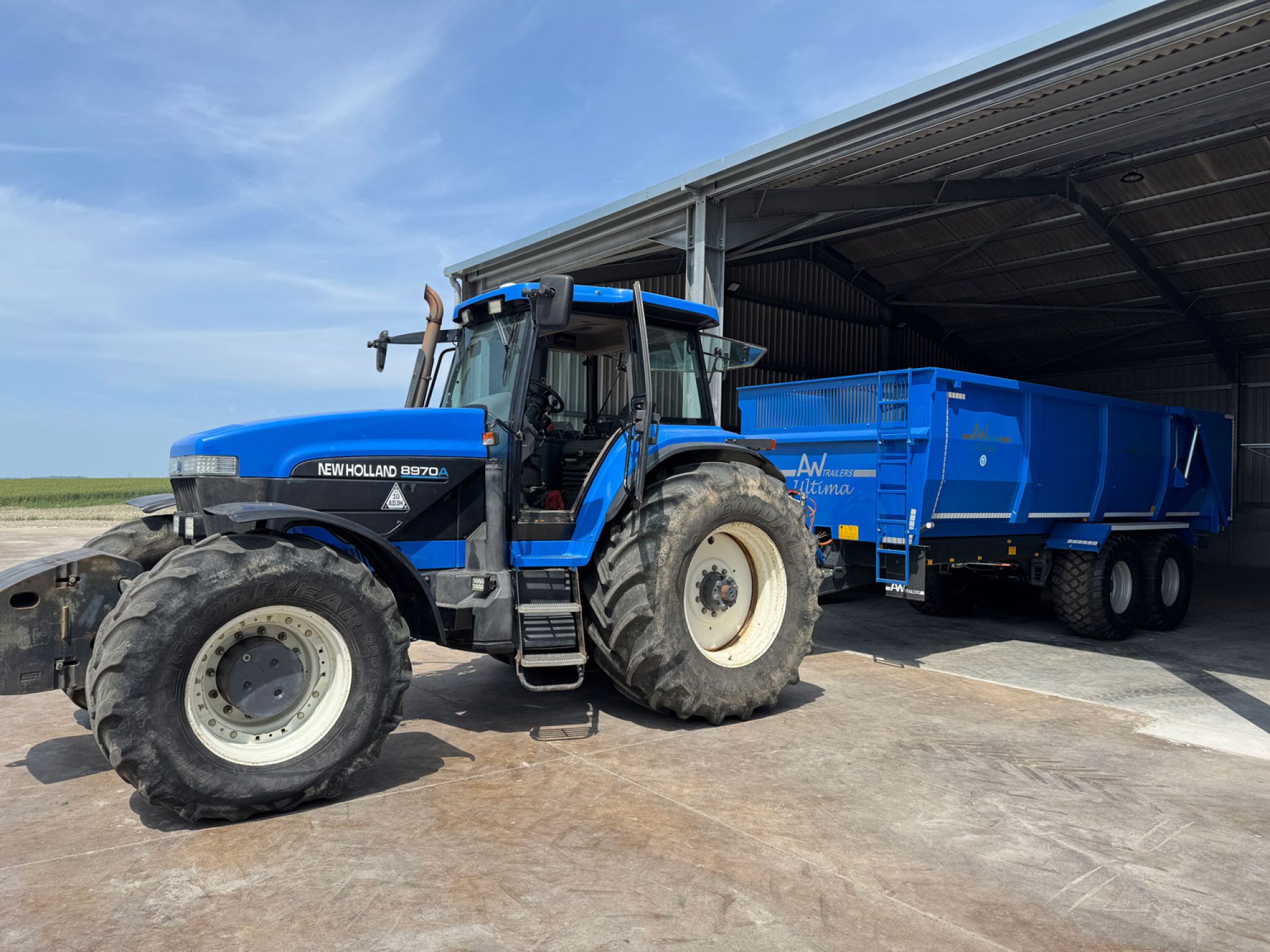 A large blue ultima monocoque trailer in a field carried by a factory