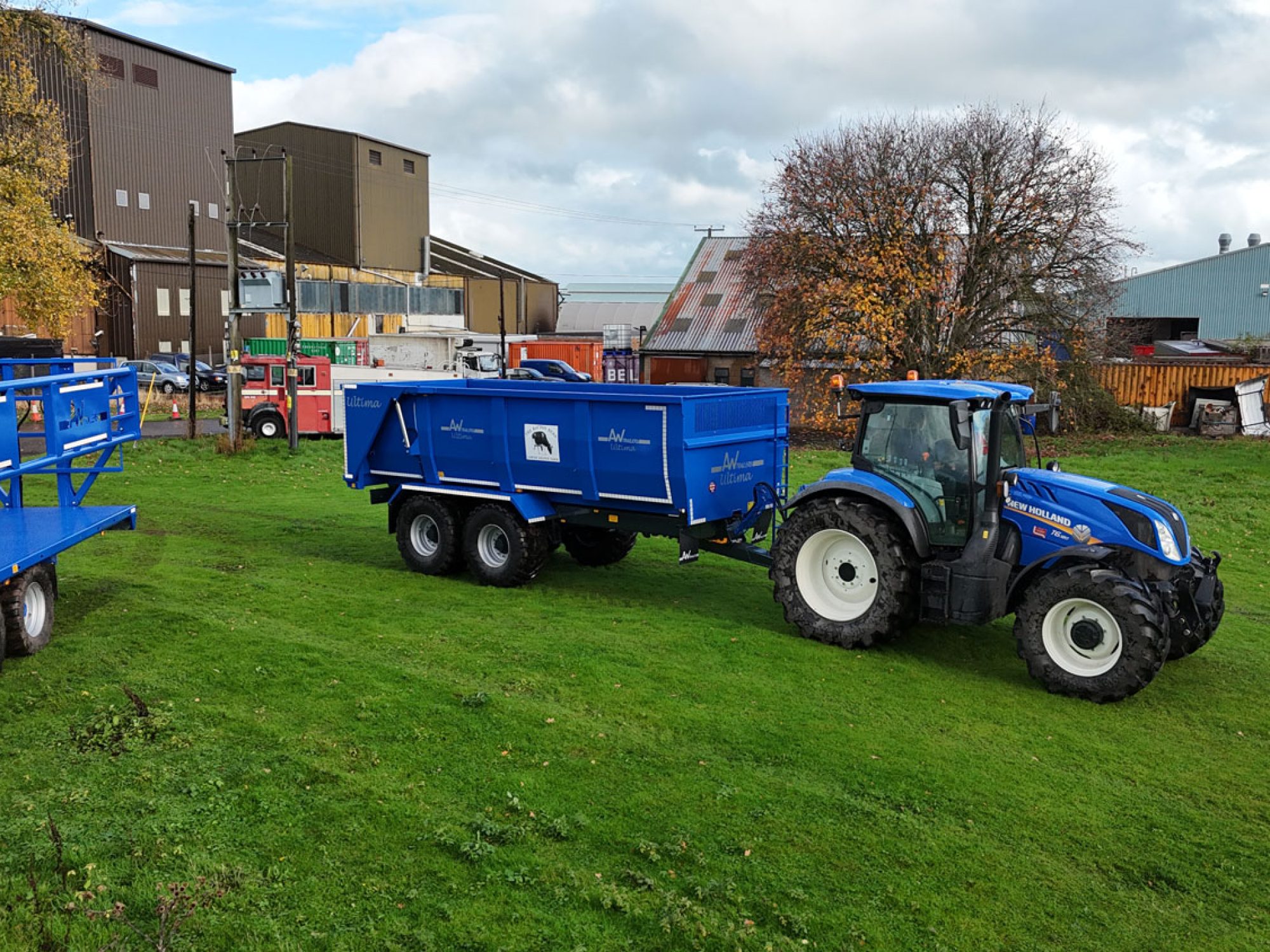 A large blue ultima monocoque trailer in a field carried by a tractor